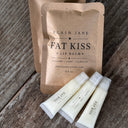 Fat Kiss lip balm packaging on a wooden surface