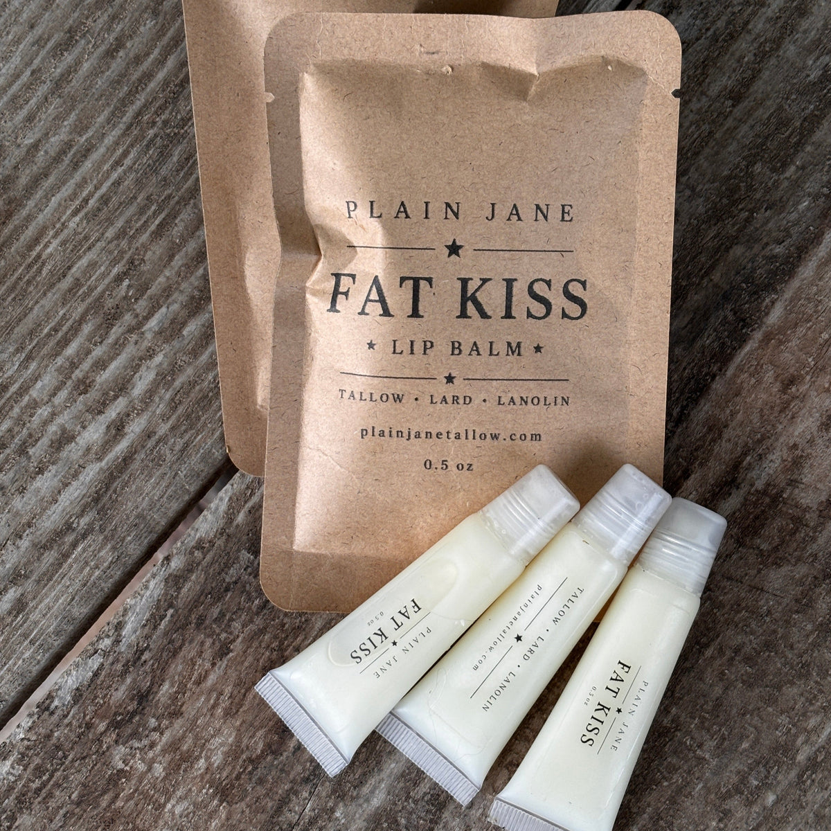 Fat Kiss lip balm packaging on a wooden surface