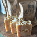 Three bars of soap with 'Plain Jane Soap Co.' packaging on a wooden surface.
