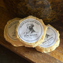 Three round dog wash soap bars with labels on a wooden surface